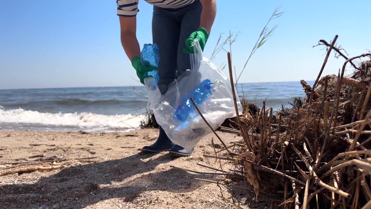 Volontario che pulisce rifiuti di plastica dalla spiaggia