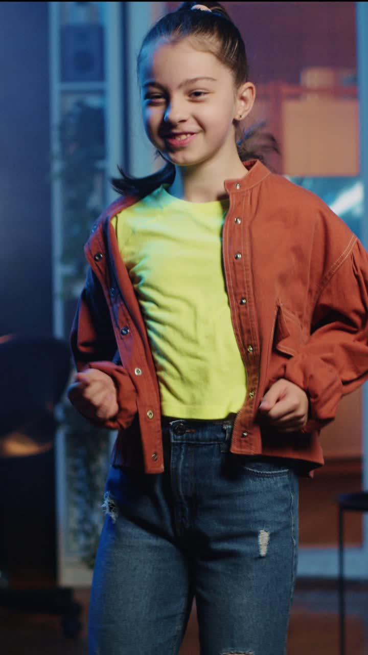 Vídeo vertical Niño contento bailando en el interior de un estudio doméstico con poca luz, creando contenido para un canal online