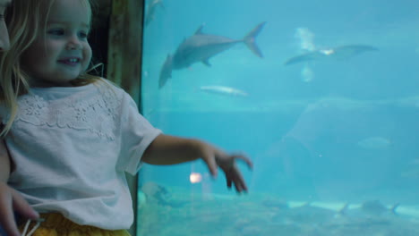 madre feliz con su hija en el acuario mirando hermosos peces nadando en el tanque niña observando animales marinos con curiosidad divirtiéndose aprendiendo sobre la vida marina con mamá en el oceanario