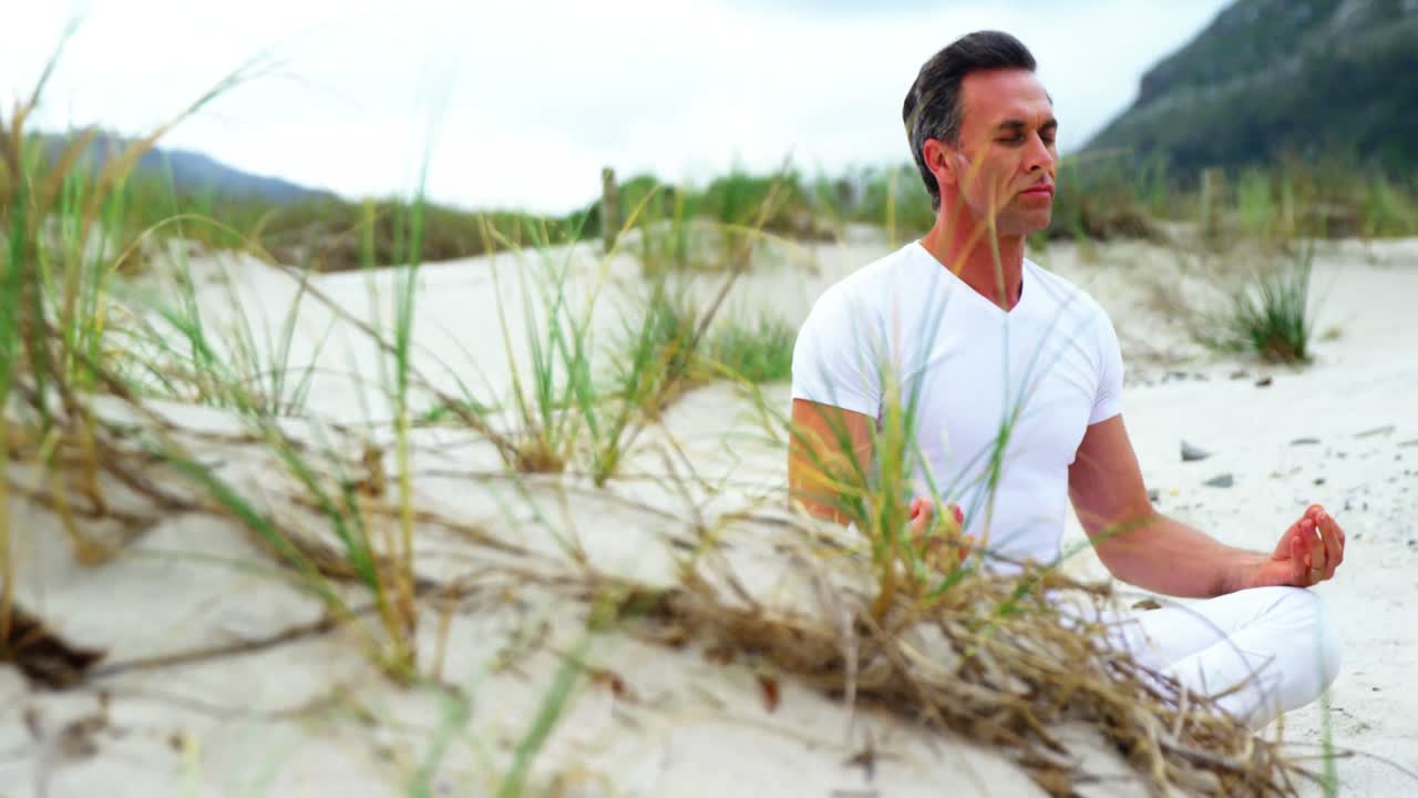 해변 에서 요가 를 하는 성숙 한 남자