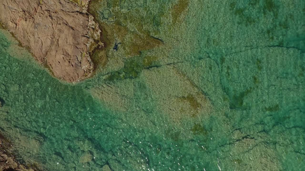 Costa rocciosa vicino al mare verde intenso.