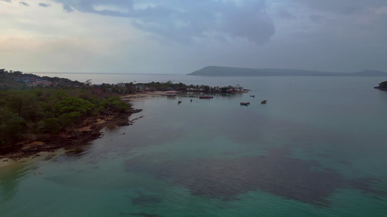 Koh Rong Sanloem island village in Cambodia, featuring turquoise water, pier, boats and tropical jungle. Perfect aerial view flight dolly left drone