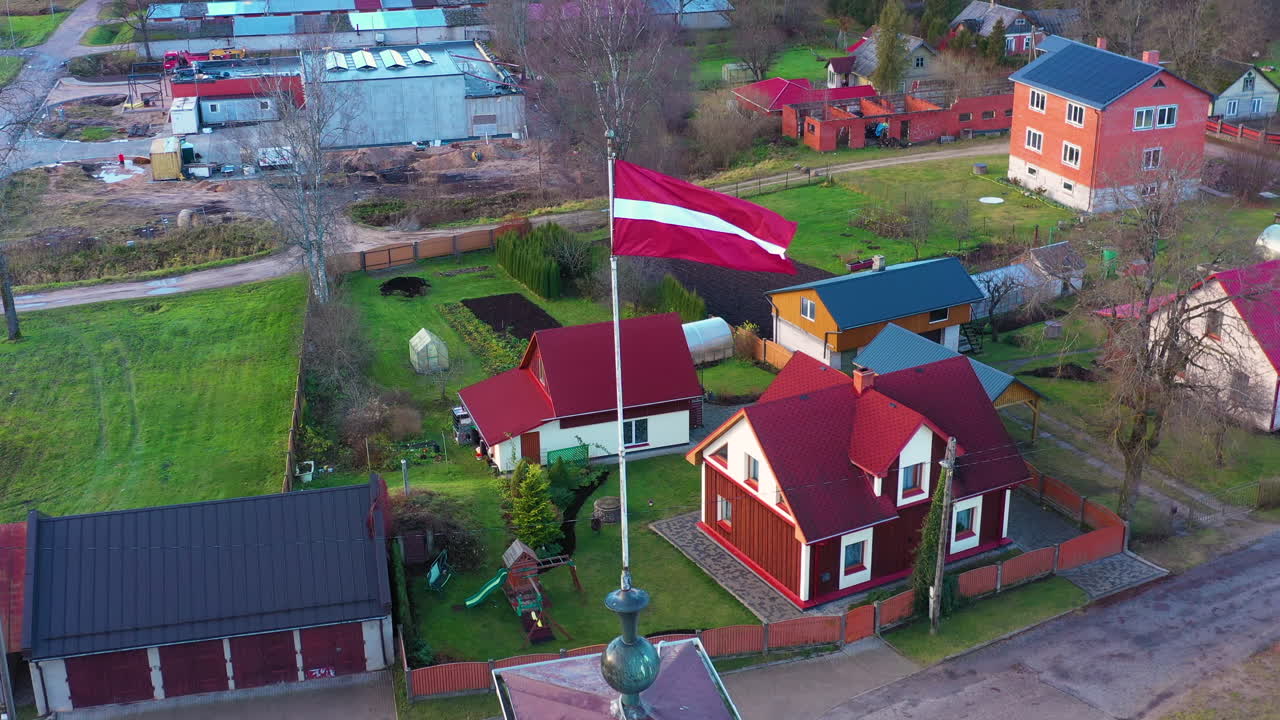 vista aérea de un barrio rural con la bandera de letonia en primer plano