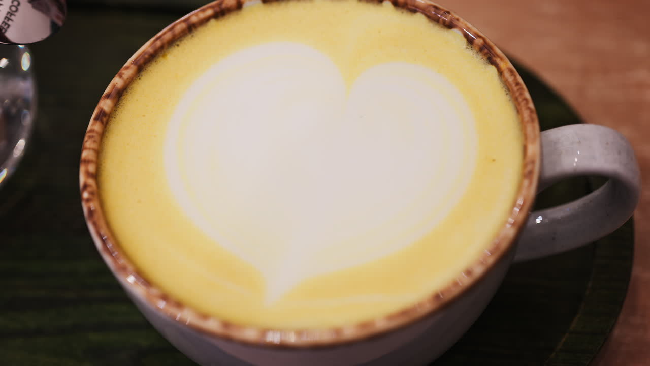 Close up of a cup of cappuccino on a black wooden tray on a table