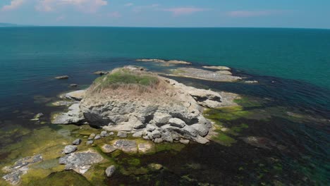 aerial panning arc shot of big cliffs in the sea with vegetation and birds