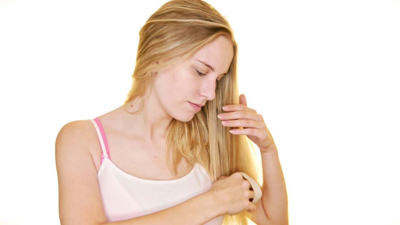 한 젊은 여성이 천연 말털 브러시로 긴 금발 머리를 빗는다