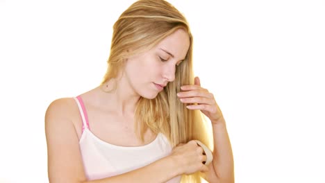 una joven cepilla su largo cabello rubio con un cepillo de pelo de caballo natural