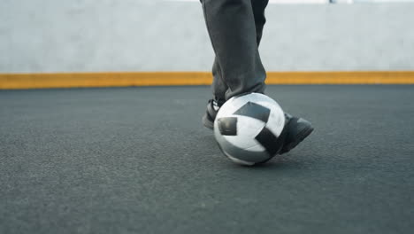 leg view of man skillfully controlling soccer ball with precise foot movements on sport arena, showcasing athletic coordination and focus, background includes yellow barrier and clear, urban