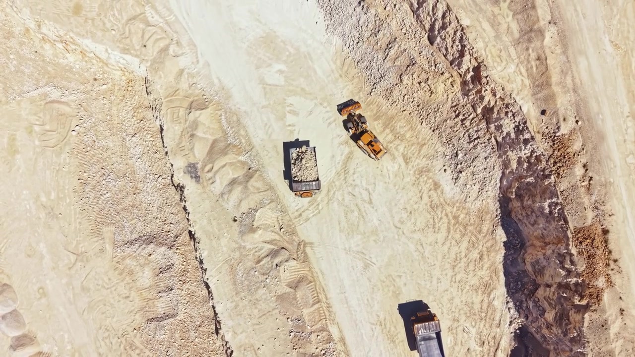 Quarry site with heavy machinery and exposed earth showing the extraction process during the day