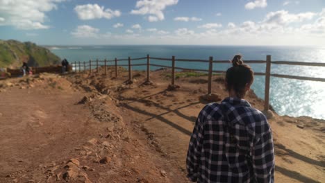 mujer disfrutando de la vista panorámica desde un acantilado costero
