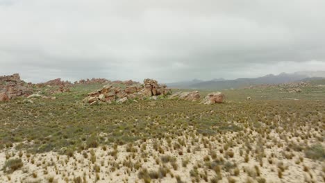 drone flies over desert landscape over rock formations in cederberg wilderness area in south africa - in the background you can see rocky mountains