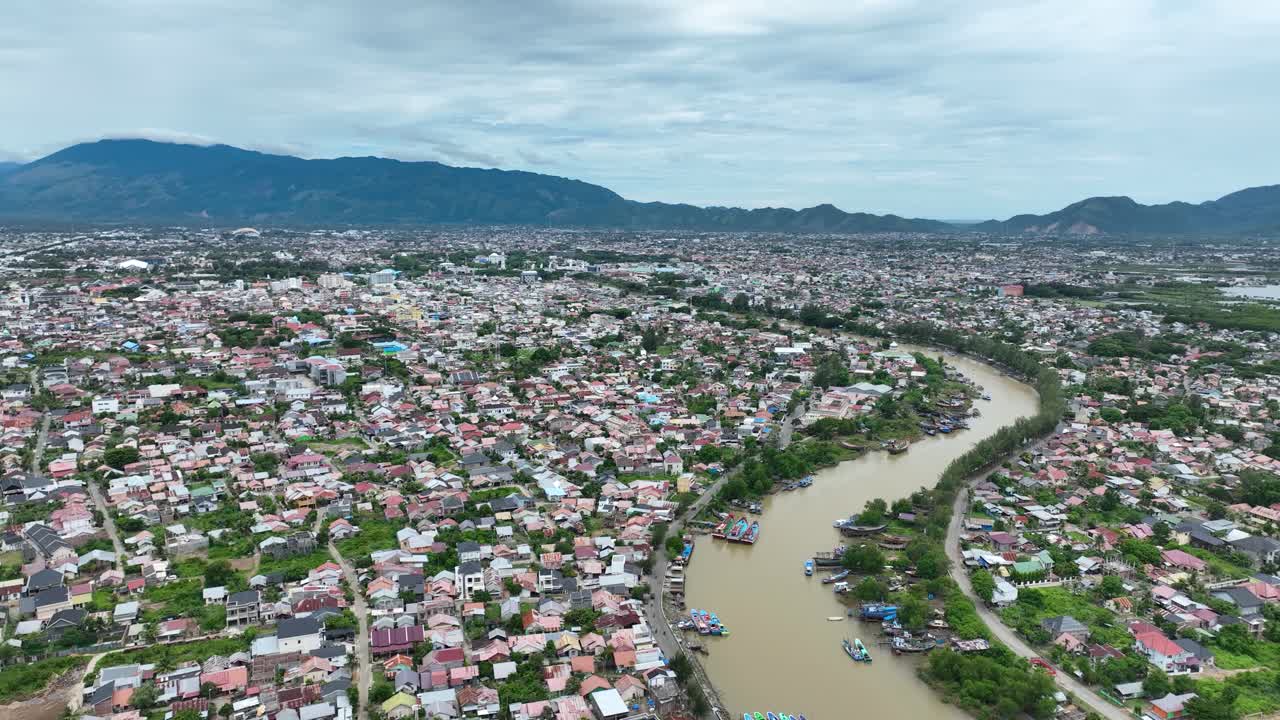 banda aceh, que muestra un denso paisaje urbano y un río sinuoso con montañas en el fondo, la recuperación posterior al tsunami es evidente, vista aérea