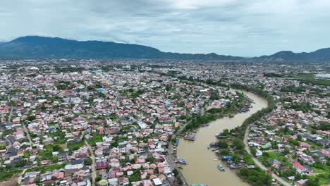 Banda-Aceh,-Mostrando-Un-Denso-Paisaje-Urbano-Y-Un-Río-Sinuoso-Con-Montañas-Al-Fondo,-Evidente-Recuperación-Post-tsunami,-Vista-Aérea