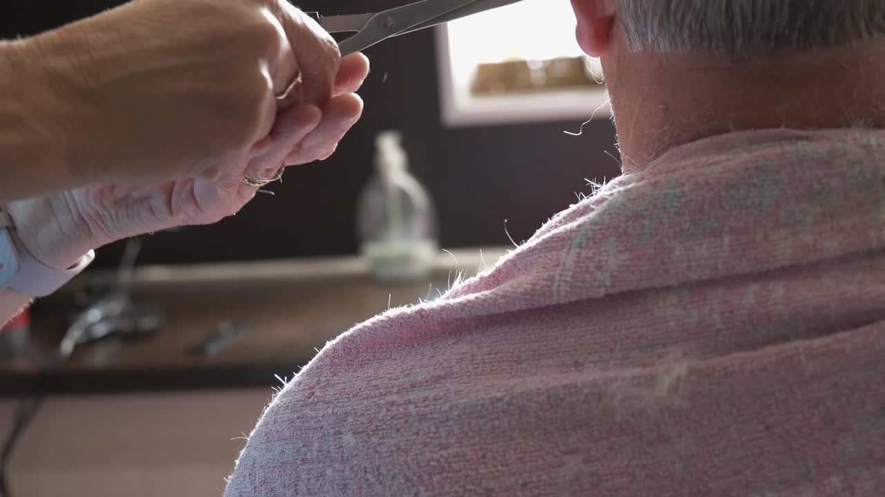 Back of head shot of senior grey haired man having haircut in home kitchen, Close up, left to right slide with copy space