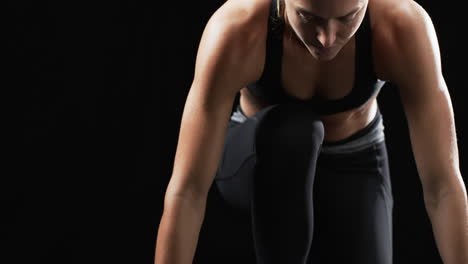 determined young woman trains intensely in gym, slow motion, black background.