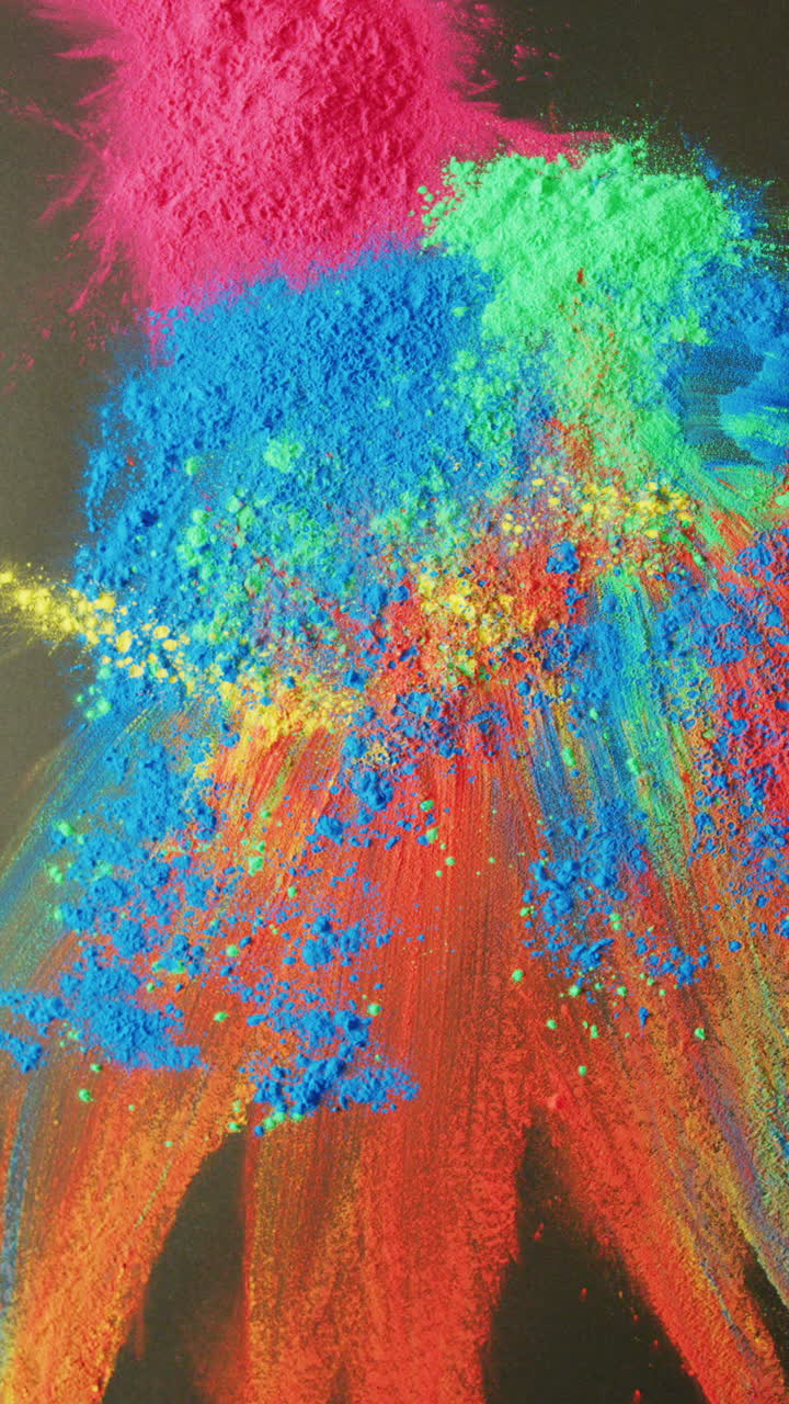 Video verticale in primo piano di polveri colorate su sfondo nero, con spazio per il testo.