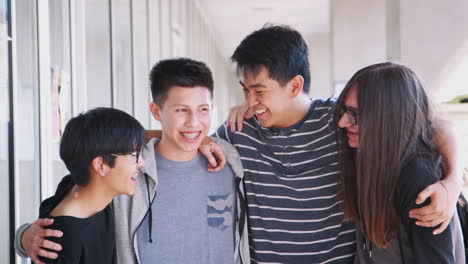 portrait of smiling male college student friends in corridor of building