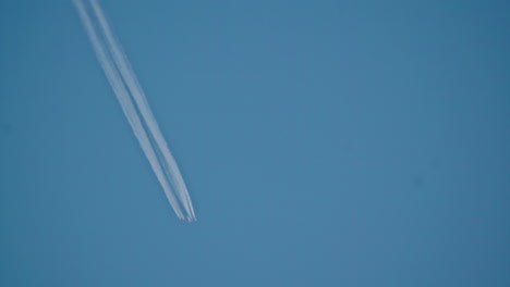 Nach-Oben-Geneigte-Aufnahme-Eines-Flugzeugs,-Das-über-Den-Himmel-Fliegt-Und-Einen-Kondensstreifen-Hinterlässt