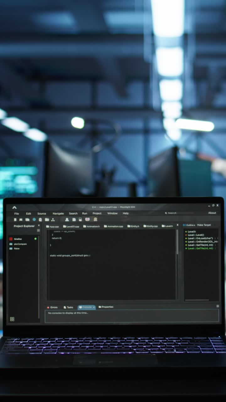 Programmeringskode ruller på en laptop-skjerm i et mørkt kontor