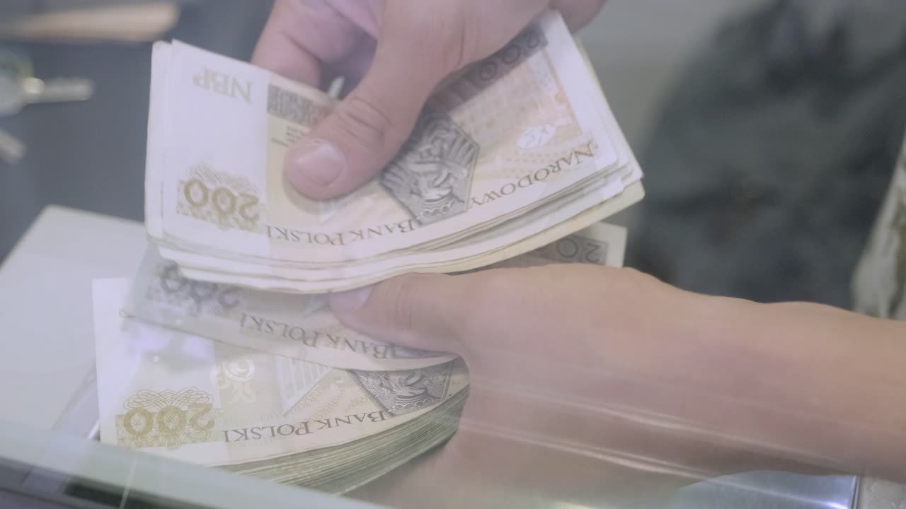 손은 폴란드 슬로티 지폐의 숫자를 계산합니다. 은행 현금 책상