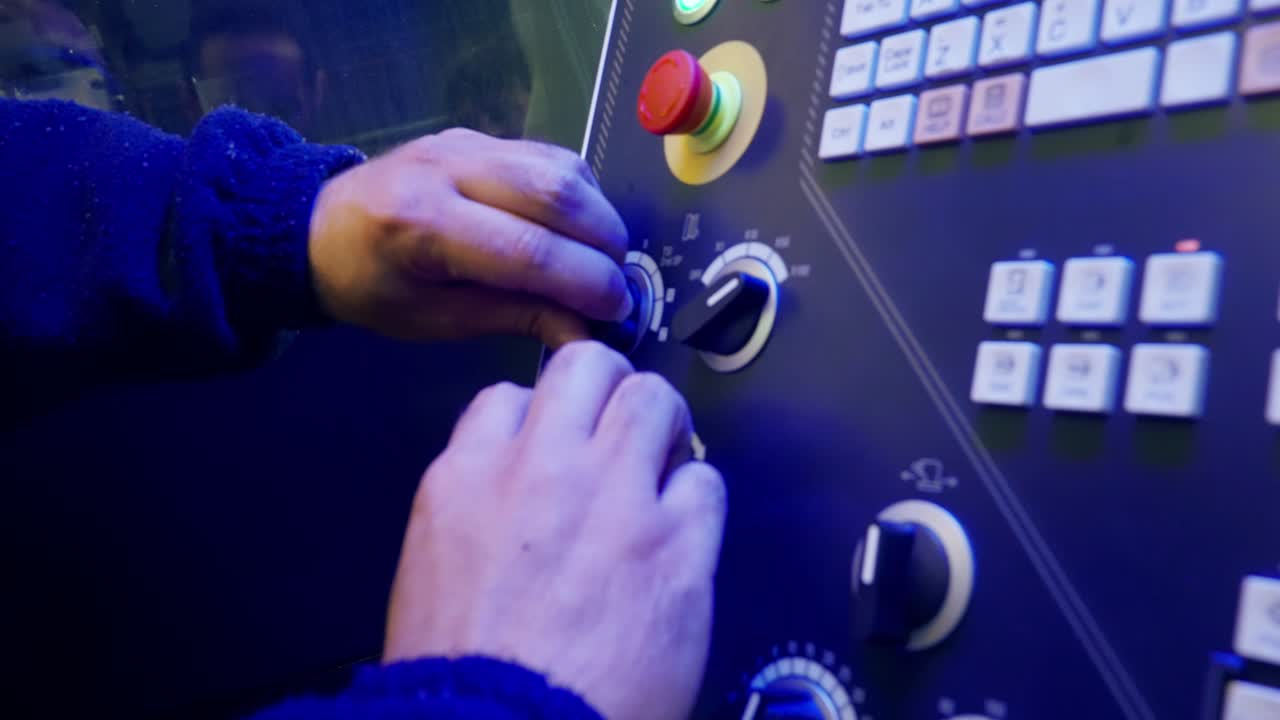 Moving, slow motion shot of a Caucasian man's hands moving knobs on a technology board full of buttons and knobs