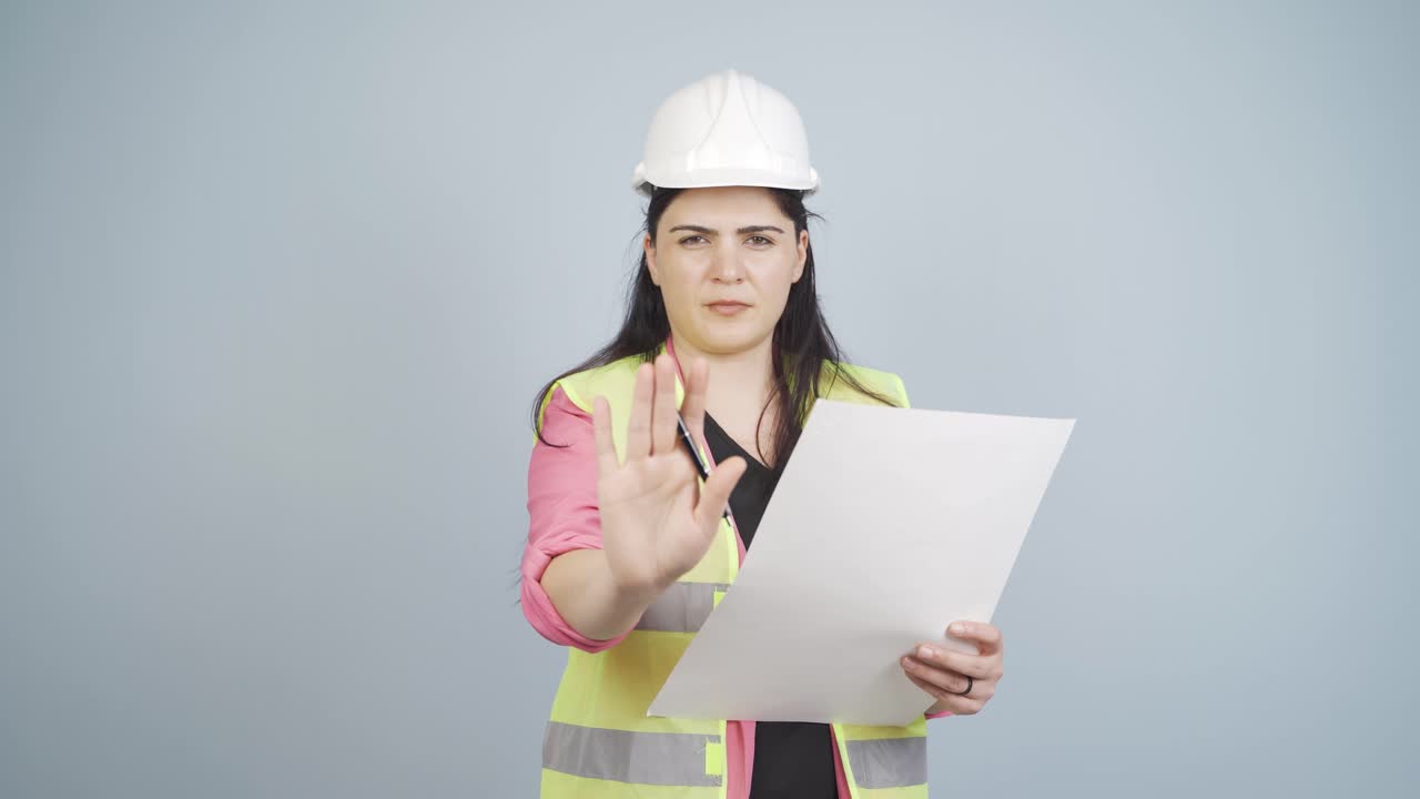 el ingeniero mira a la cámara y hace una señal de alto.