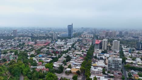 orbit drone shot over residential and commercial areas in santiago on a cloudy day, featuring the movistar tower in the background