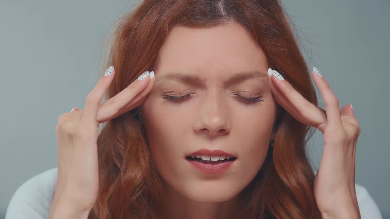 Close up redhead woman with closed eyes covered face in hands feeling pain