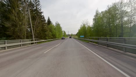 Driving-on-a-green-country-road-and-approaching-a-busy-intersection-at-speed