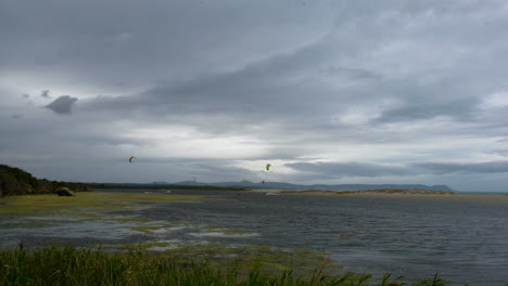 Kitesurfer-Auf-Der-Lagune,-Stimmungsvoller-Himmel,-Totale