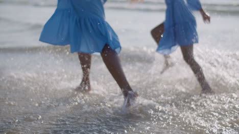 close up of mother and daughter running on water at sea beach