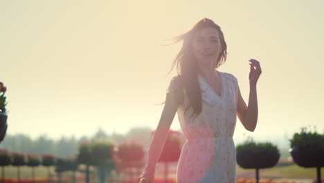 Smiling-woman-walking-in-garden.-Emotional-girl-touching-hair-in-sun-reflection.