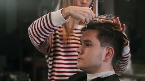 hairdresser cutting hair with professional scissors and comb in hairdressing salon. close up haircutter making male haircut with scissors in hairdressing school