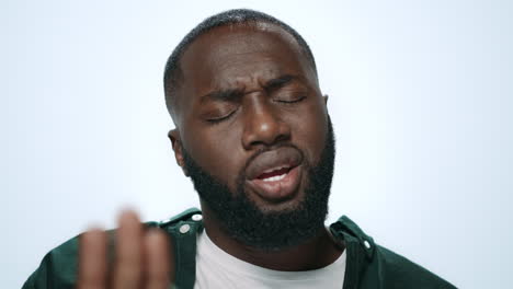 portrait of displeased african man waving finger no on light background.