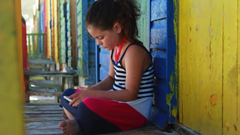 girl using digital tablet near colorful beach hut