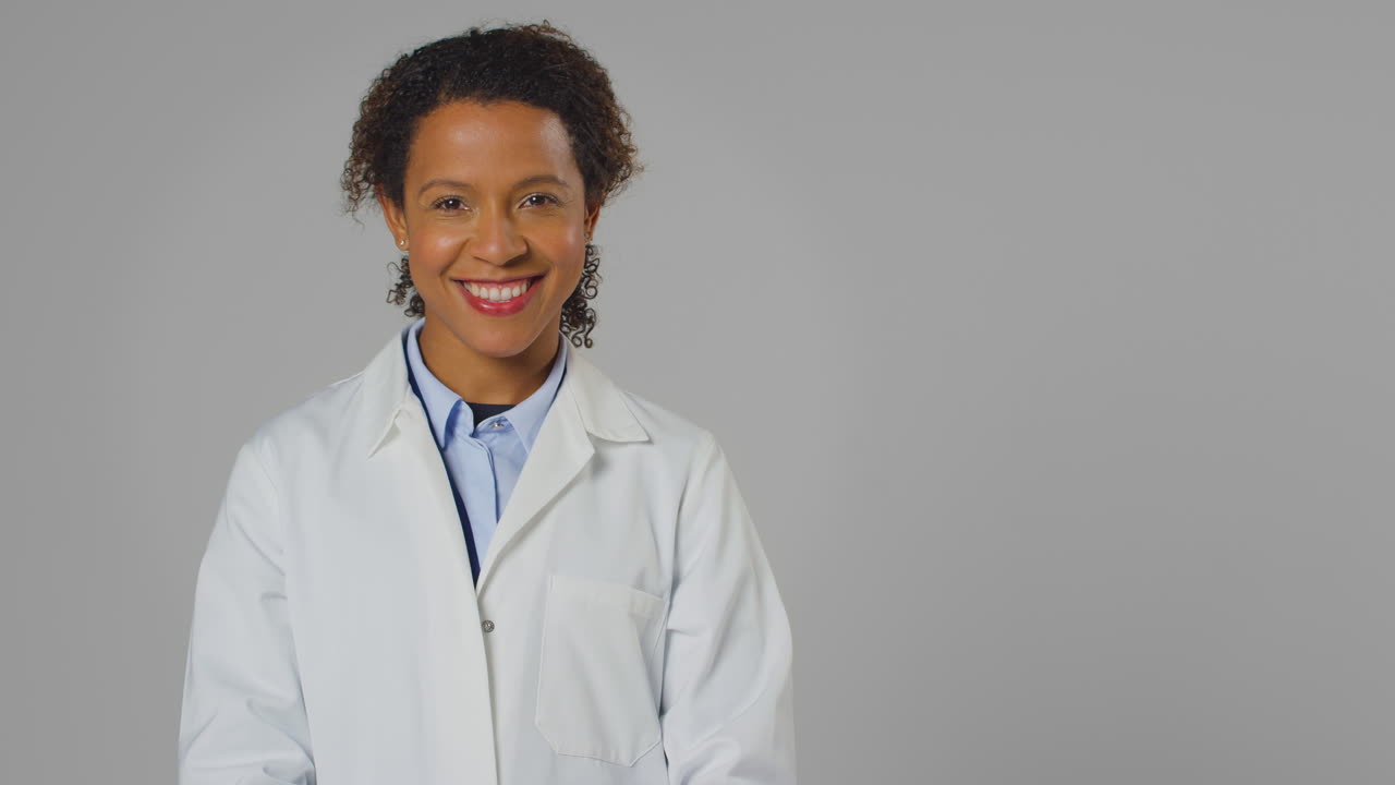 Studio Portrait Of Smiling Female Doctor Or Lab Worker Wearing White Coat