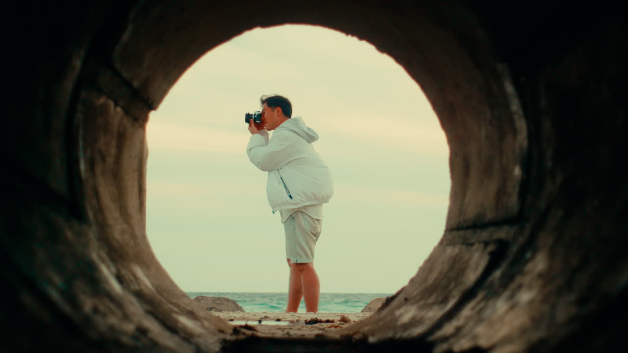 Photographer at the Beach through a Tunnel