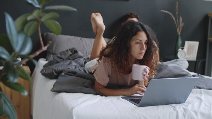 Kvinde, der arbejder på laptop i sengen