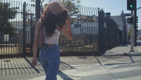 Unrecognizable-woman-crossing-street.-Back-view-young-girl-going-on-crosswalk.