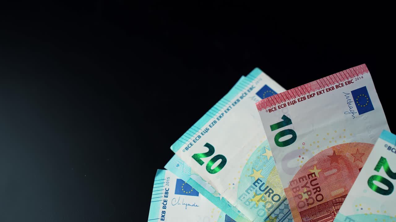 Herabfallende Euro-Banknoten auf dunklem Hintergrund mit Freiraum, verdeutlichen Barausgaben, Budgetierung, Ersparnisse sowie Inflation oder Lebenshaltungskosten als Finanzkonzept