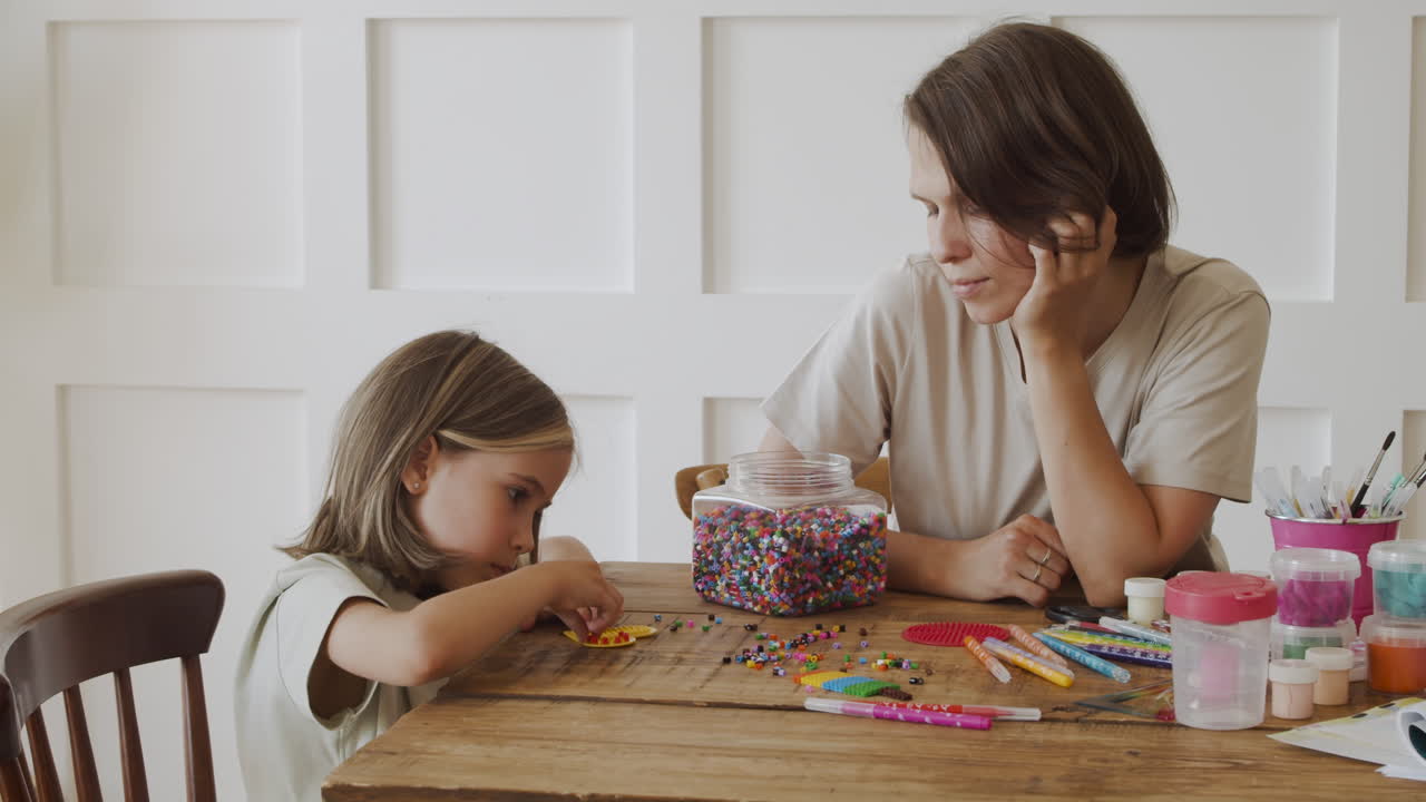 una niña rubia y su madre jugando con cuentas de colores