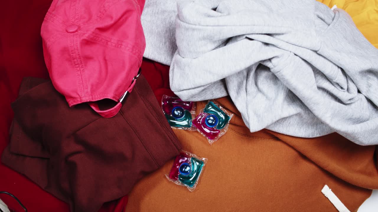 Capsule di detersivo colorate che cadono su un mucchio di vestiti