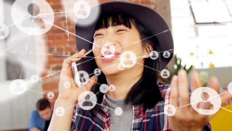 animation of network of connections with icons over asian woman talking on smartphone