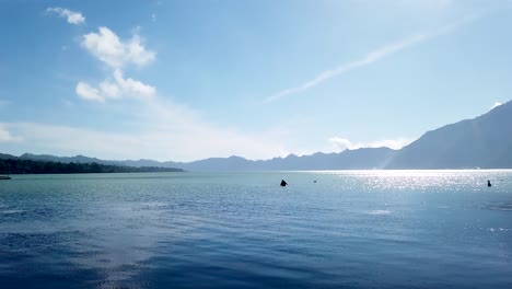 巴厘島的傳統漁民在金塔馬尼山巴圖爾湖使用小船獨木舟釣魚,有網和藍色清晰的天空和山湖風景背景