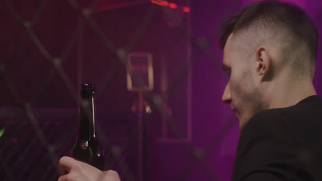 young man drinking beer while sitting alone at disco club