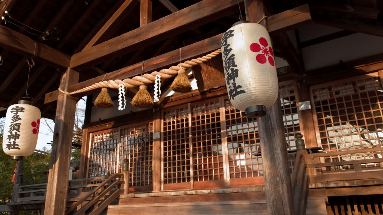 Exteriér tradiční japonské svatyně s lucernami a posvátným lanem.