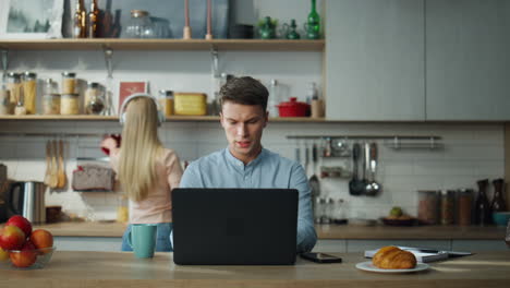 manager have online meeting with clients on laptop at kitchen while wife cooking