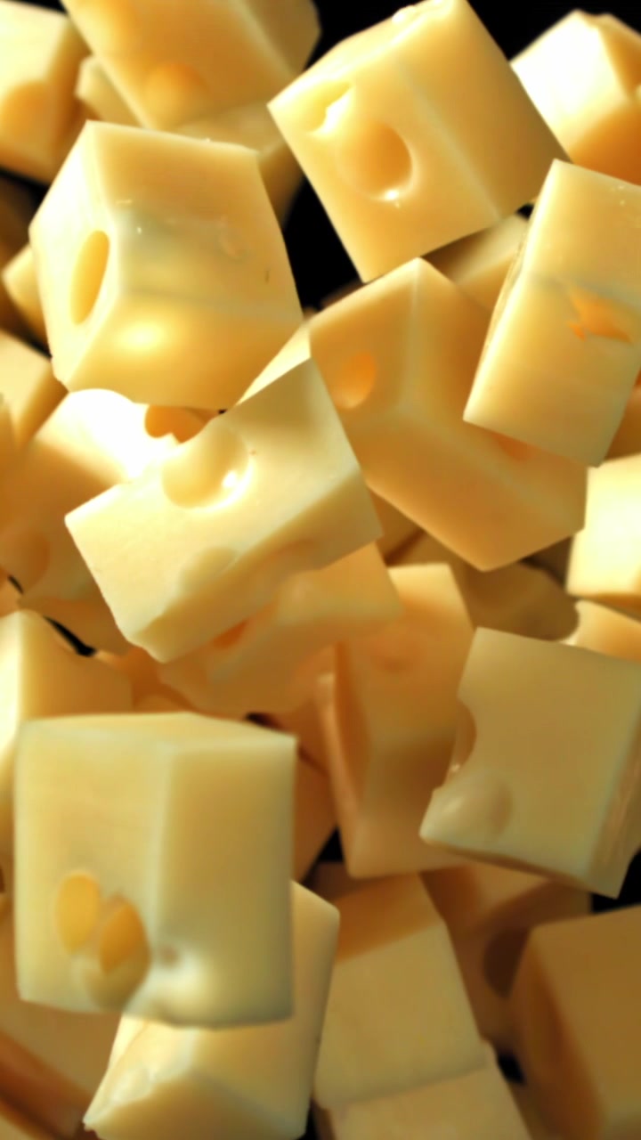 Cubes de fromage jaune tombant au ralenti sur fond noir