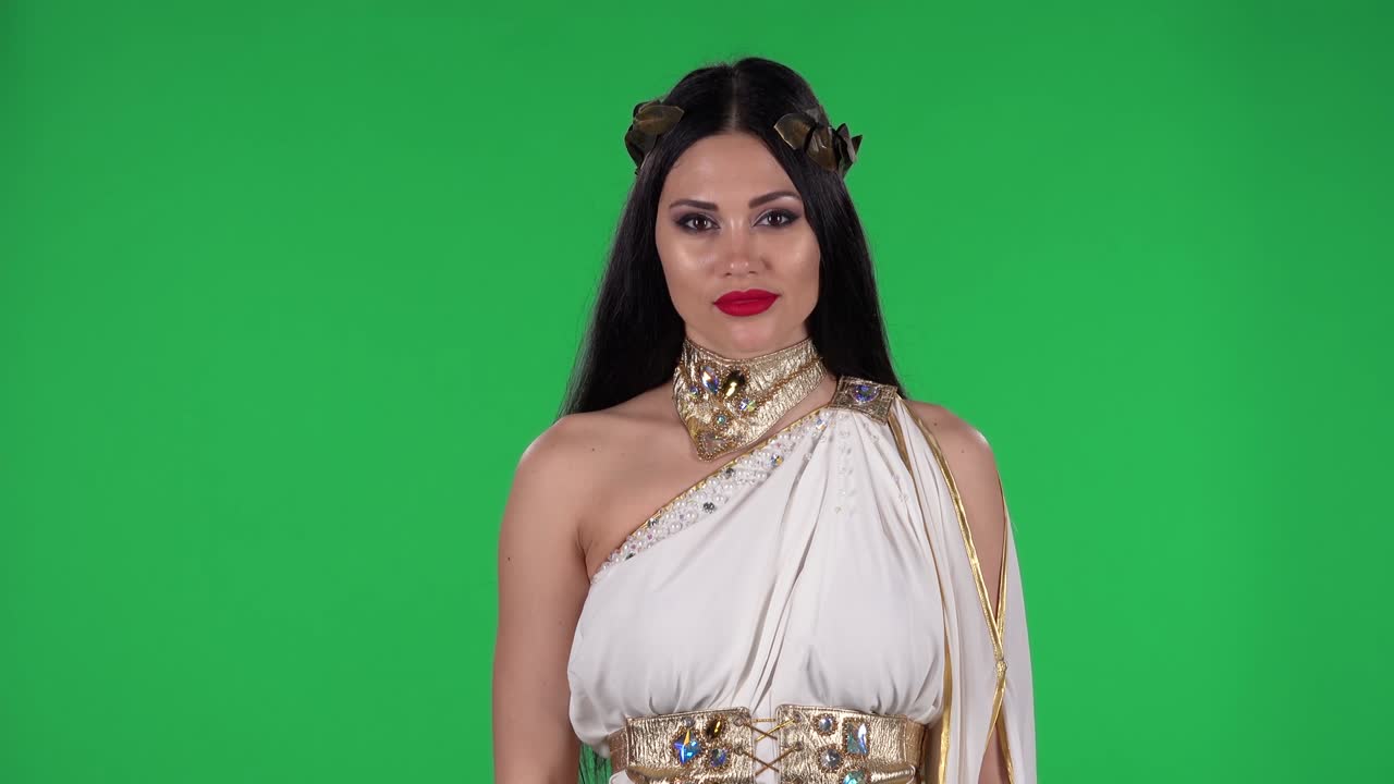 Ritratto di bella donna in abito da dea greca e ghirlanda di alta moda, che guarda dritto con un'espressione "wow" scioccata e sorpresa. Green screen.