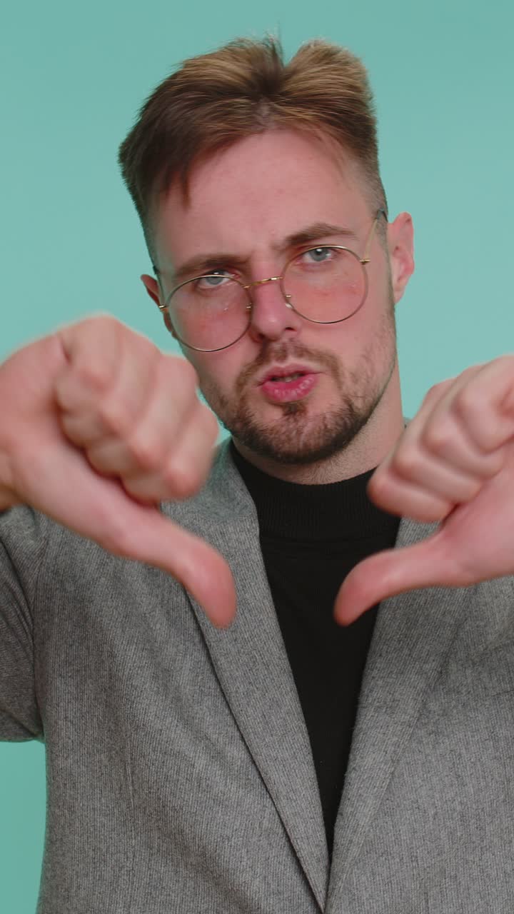 Upset business man in jacket showing thumbs down sign gesture disapproval dissatisfied dislike